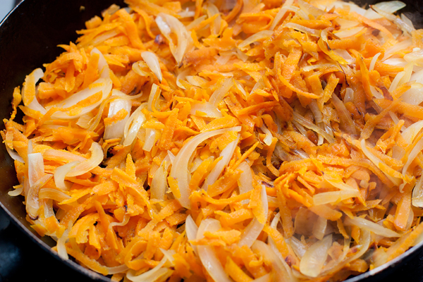 Через 5 минут нам останется только дополнить вкусовую гамму. Для этого в кастрюлю добавляем обжаренные лук и морковь, мелко нарезанный чеснок и соль.