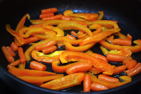 Сладкий перец нужно очистить от сердцевины и нарезать длинными брусочками. На горячую сковороду налить немного масла, положить перец и маленькие морковки (baby carrots). Обжарить овощи в течение 3-5 минут на большом огне, периодически помешивая.