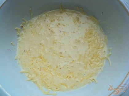К яйцам добавить натертый сыр и сметану. Посолить немного, поперчить и взбить все вилкой.