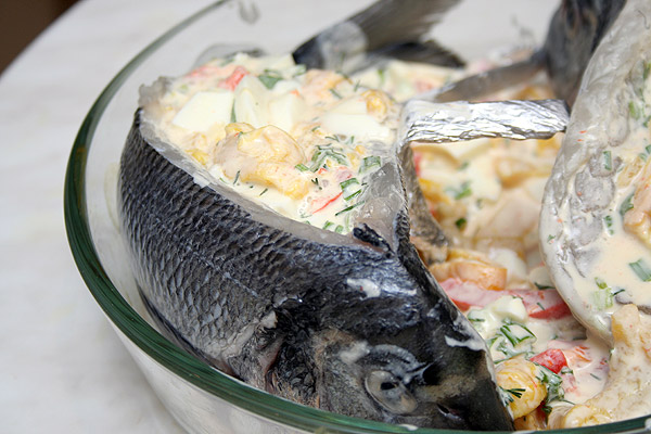 Положить рыбу на брюшко и через разрез нафаршировать смесью. Сбрызнуть соком лимона. Выложить рыбу на жаропрочное блюдо и поставить в разогретую до 200°С духовку и запекать 40 минут.