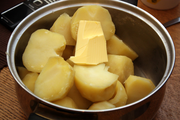 Картофель нужно очистить и сварить до мягкости в подсоленной воде. Когда он будет готов, воду нужно слить и добавить к нему хороший кусочек сливочного масла.