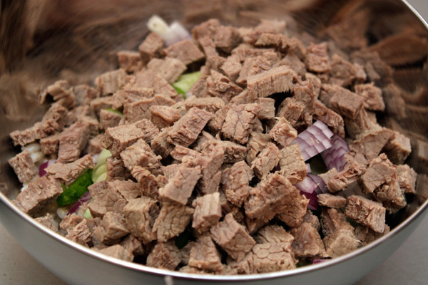 Когда мясо будет готово, его нужно нарезать мелкими кубиками и положить в салат. 