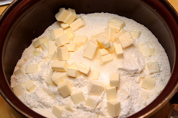 Муку с разрыхлителем и щепоткой соли просеиваем и добавляем сахар. Закидываем нарезанное маленькими кубиками сливочное масло.