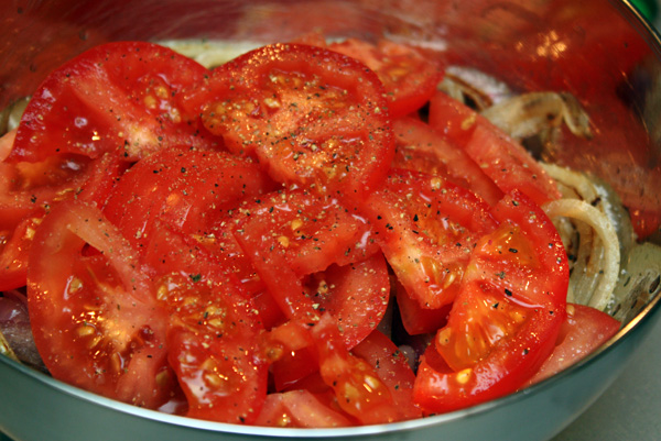 Выкладываем обжаренные овощи в миску, туда же добавляем нарезанные помидоры, соль, перец и уксус.<p>Масло в этот салат добавлять не нужно, его достаточно в обжаренных овощах.