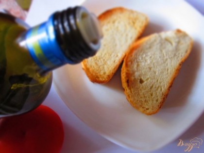 Поджариваем хлеб на сухой сковородке до золотистой корочки, а внутри он должен остаться мягким. Натираем хлебушек чесноком и смазываем оливковым маслом.
