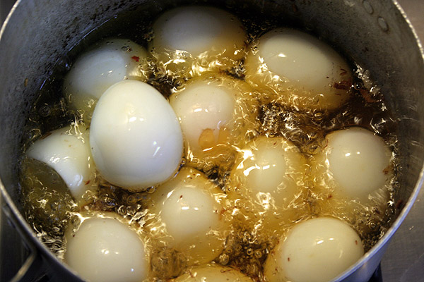 Сварить в крутую 12 яиц, очистить их. Закинуть в тоже масло, в котором жарились овощи. Обжарить в течении 3−4 минут.
