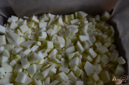 Форму выстлать бумагой для выпечки и уложить половину крошки. Затем слой очищенных и нарезанных яблок.