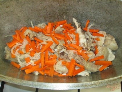 Через 10-15 минут добавить в казан лук с морковью. Жарить еще около 5 минут.