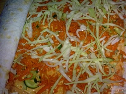 На лист лаваша с сыром положите второй лаваш. Смажьте его оставшейся смесью, выложите слоями: огурцы, морковь по-корейски и капусту. Сверните рулетом.