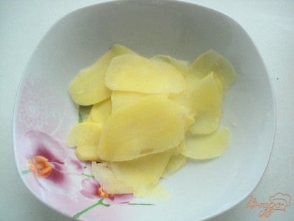 Картофель почистить и при помощи овощечистки порезать тонкими пластинка. Залить водой.