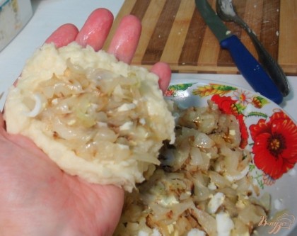 Отделяем кусочек картофельного теста. Мокрыми ладошками формируем лепёшку. На неё выкладываем капустную начинку. Залепливаем