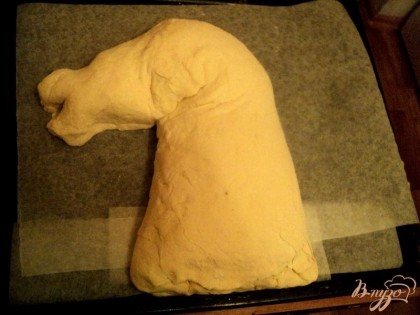 Противень застелить бумагой для выпечки. Пирог перевернуть швом вниз и сформировать голову лошади.