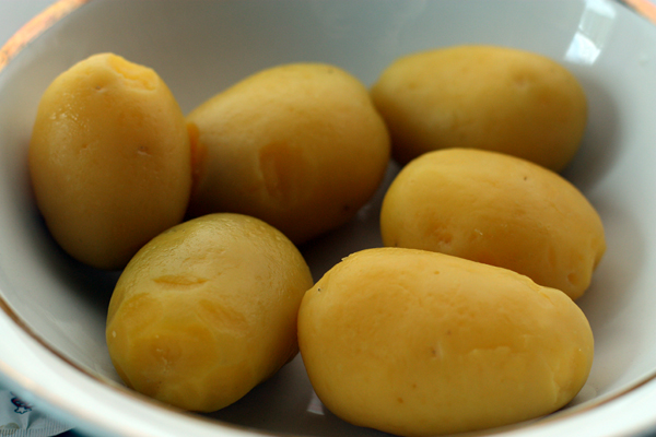 Картофель отварите в мундире, яйца сварите вкрутую. дайте готовым продуктам остыть и очистите.