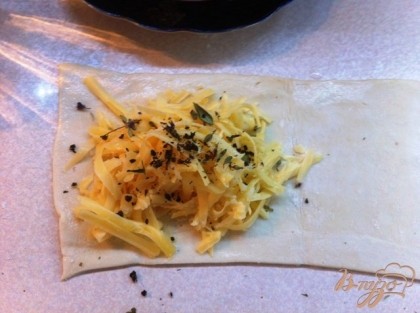 На половинку слоеного теста кладаем тертый сыр, посыпаем базиликом