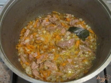 Чеснок измельчить. Через 1,5 часа тушения, добавить к мясу лук, морковь и чеснок. Тушить 15 мин.