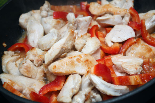 В курицу вливаем водку и готовим на среднем огне около 5 минут. Добавляем нарезанный полосками сладкий красный перец и соль. 