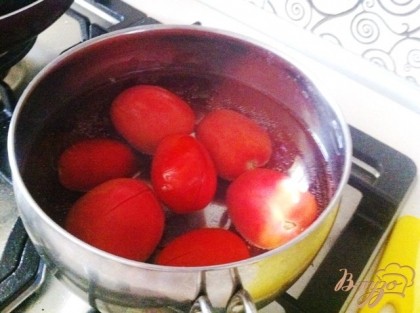 Кладем в горячую воду помидоры на несколько минут .