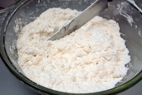Для нижнего слоя пирога надо сделать несладкое рубленое тесто. Смешиваем холодное сливочное масло, муку и соль. Режем ножом эту смесь до образования крошек.