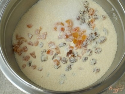 К манной крупе добавить разрыхлитель, сахар и ванильный сахар, всыпать подготовленные сухофрукты:нарезанную курагу и промытый изюм.