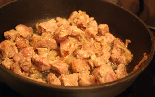 Обжариваем нарезанный соломкой репчатый лук в растительном масле и добавляем туда свинину. Жарим мясо до полуготовности.