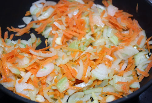 Для соуса разогреваем оливковое масло, и обжариваем мелко нарезанный лук, чеснок и натертую морковь. Через 15-20 минут, когда овощи станут мягкими, добавляем туда очищенные и нарезанные томаты. Тушить еще минут 10-15.
