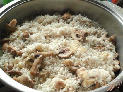 Грибы тушить пока испарится половина жидкости. Затем добавить промытый рис. Всё хорошо перемешать.