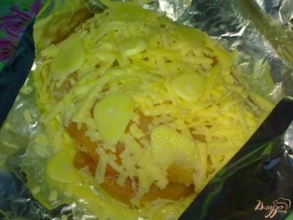 Затем на сыр положите филе. Филе смажьте лимонным соком и медом, посыпьте оставшимся сыром. Положите пластинки чеснока и полейте бульоном.