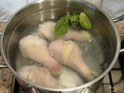 В кастрюлю налить 2 л воды и довести до кипения. В кипящую воду выложить куриные голени, добавить лавровые листы и варить до готовности голеней.