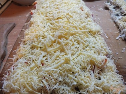 Обильно натираем сыр. Желательно использовать твердый. Запекайте пиццу 15-20 мин до готовности коржа.