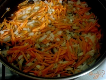 В глубокую сковороду налить 2/3 растительного масла и разогреть его. На него высыпать лук и морковь и пассировать на небольшом огне.