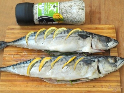 Тонко нарезать лимон и вставить его в разрезы.В брюхо рыбы поместить по пучку зелени.Солить рыбу нужно непосредственно перед запеканием.