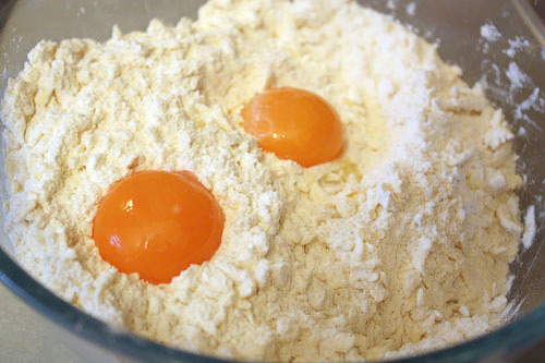 Добавляем 2 яичных желтка и быстро замешиваем тесто. Можно добавить в тесто пару столовых ложек коньяка или рома — это придаст аромат и сделает тесто более пластичным.