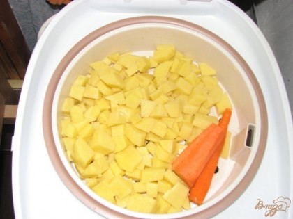 Режем картофель и складываем ее на чашу для готовки на пару. Рядом кладем очищенную морковь.
