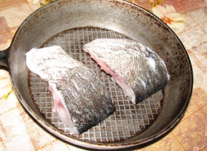 Чем крупнее рыба – тем она вкуснее, и тем меньше в ней костей. Учтите это при выборе рыбы. Разрезаем кусок толстолобика напополам и промываем под проточной водой. Выкладываем  порционные кусочки на сковороду.