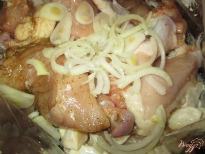 Уложить картофель и курицу в кулинарный рукав и добавить кольца репчатого лука.