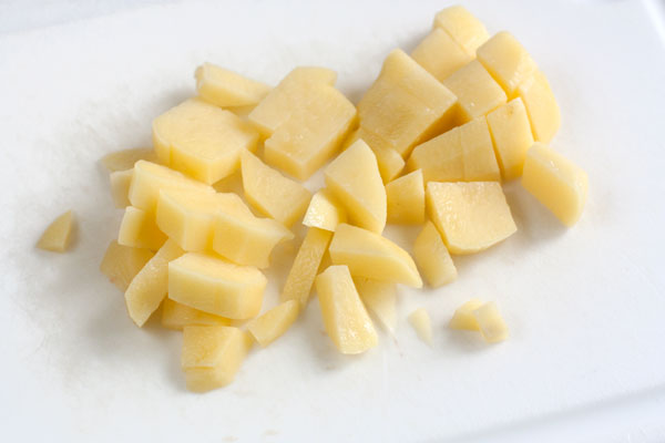 Картофель очистите, нарежьте мелкими кубиками и положите в воду с сыром. Варите 10-15 минут на среднем огне.