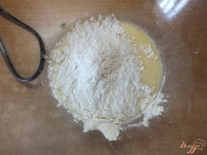 Муку с разрыхлителем смешиваем и горкой просеиваем в тесто. Перемешиваем до однородного теста.