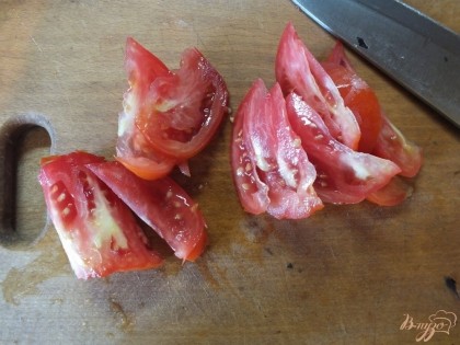 Дольками нарезаем помидор.