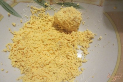 Плавленый сыр натереть на мелкой терке, добавить 2 ст. ложки майонеза хорошо перемешать. Скрутить с полученной массы шарики, обвалять их в тертом желтке.