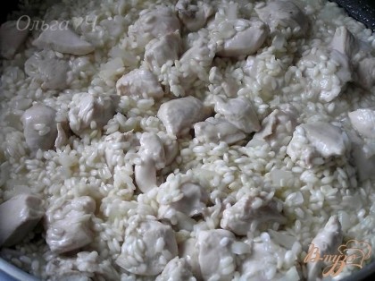 Затем влить воду небольшими порциями, готовить помешивая около 20 минут, пока рис не впитает в себя всю жидкость.