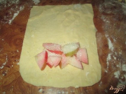 Разделить пласт на несколько прямоугольников. На каждый прямоугольник положить порезанные яблоки и посыпать сахарным песком.