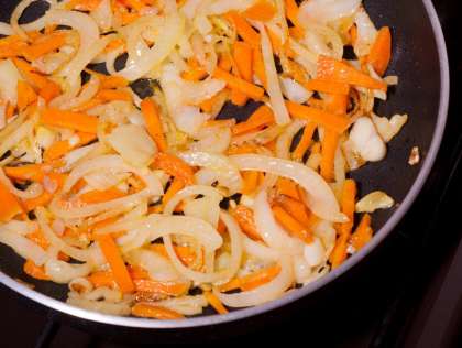 Выложить половину нарезанной моркови, обжарить до золотистого цвета лука.