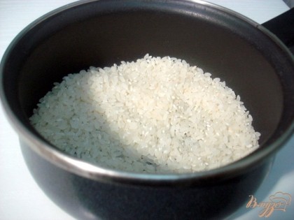 Отмериваем в емкость мерку риса, не обязательно сто граммов, столько, сколько вам нужно. В данном случае рис промывать не нужно, он должен быть слегка клейким. Мы используем обычный круглый рис. Воды нужно взять в два раза больше: если риса одна мерка, тогда воды нужно взять две мерки. Холодной водой заливаем рис.