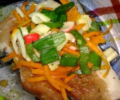 Мясо выложите на противень. На каждый кусочек выложите морковь, крабовые палочки и зеленый лук. Запекайте при 200С 15-20 минут.