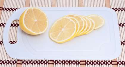 Половинку лимона нарезать тонкими кольцами.