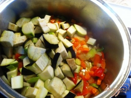 Добавить нарезанные кабачки и баклажаны. Все овощи режем небольшим кубиком со стороной примерно 0,5 см. Обжаривать все вместе 5 минут