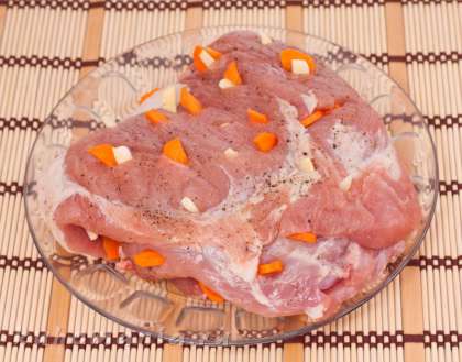 В мясе сделать надрезы, нашпиговать морковью и чесноком с двух сторон.