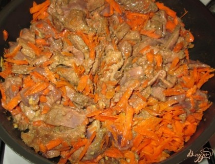 Добавить к печени натертую морковь и порезанный полукольцами лук. Перемешать, влить 1,5 стакана воды и, убавив огонь, тушить под закрытой крышкой около 20 минут.