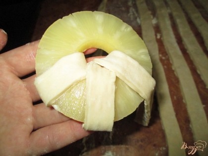 Взять консервированные ананасы, нарезанные кружочками. Обернуть каждый ананас полоской из теста.