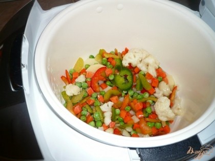 После этого в чашу мультиварки добавляем замороженную овощную смесь и продолжаем готовить в режиме "жарка" еще минут десять.